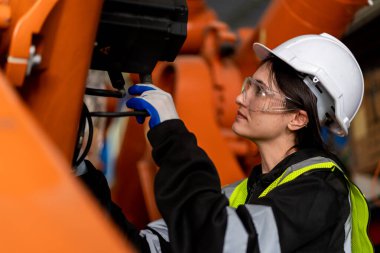 Erkek ve kadın mühendislerden oluşan bir ekip bilgisayar kontrollü çelik kaynaklama robotlarını incelemek için toplanıyor. Provalar ve kullanım için kurulum planı.