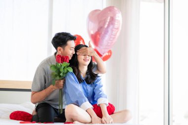 Asian couple Showing love surprise giving flowers or gifts to each other on important occasions such Valentine's Day birthdays or wedding anniversaries with love and warmth in bedroom of their home