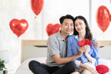 Asian couple Showing love surprise giving flowers or gifts to each other on important occasions such Valentine's Day birthdays or wedding anniversaries with love and warmth in bedroom of their home