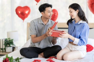 Asian couple Showing love surprise giving flowers or gifts to each other on important occasions such Valentine's Day birthdays or wedding anniversaries with love and warmth in bedroom of their home