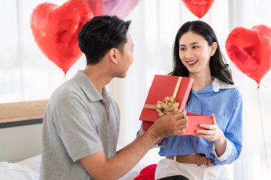 Asian couple Showing love surprise giving flowers or gifts to each other on important occasions such Valentine's Day birthdays or wedding anniversaries with love and warmth in bedroom of their home