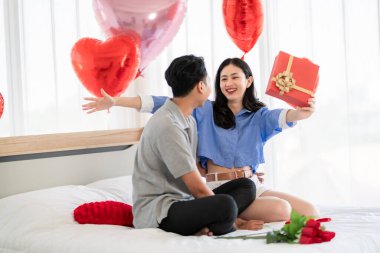 Asian couple Showing love surprise giving flowers or gifts to each other on important occasions such Valentine's Day birthdays or wedding anniversaries with love and warmth in bedroom of their home