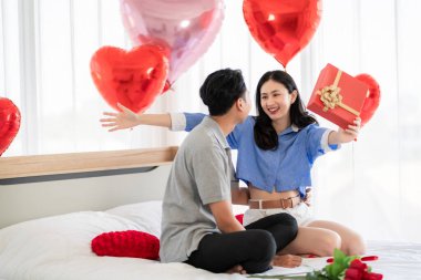 Asian couple Showing love surprise giving flowers or gifts to each other on important occasions such Valentine's Day birthdays or wedding anniversaries with love and warmth in bedroom of their home