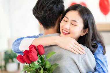 Asian couple Showing love surprise giving flowers or gifts to each other on important occasions such Valentine's Day birthdays or wedding anniversaries with love and warmth in bedroom of their home