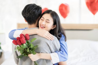 Asian couple Showing love surprise giving flowers or gifts to each other on important occasions such Valentine's Day birthdays or wedding anniversaries with love and warmth in bedroom of their home