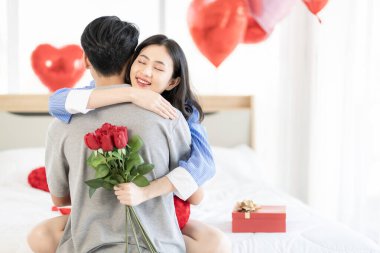 Asian couple Showing love surprise giving flowers or gifts to each other on important occasions such Valentine's Day birthdays or wedding anniversaries with love and warmth in bedroom of their home