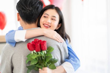 Asian couple Showing love surprise giving flowers or gifts to each other on important occasions such Valentine's Day birthdays or wedding anniversaries with love and warmth in bedroom of their home