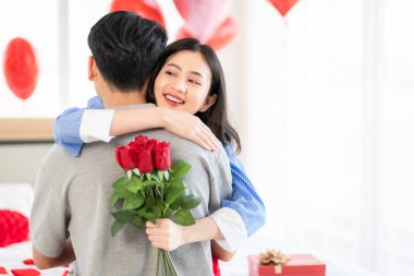 Asian couple Showing love surprise giving flowers or gifts to each other on important occasions such Valentine's Day birthdays or wedding anniversaries with love and warmth in bedroom of their home
