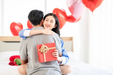 Asian couple Showing love surprise giving flowers or gifts to each other on important occasions such Valentine's Day birthdays or wedding anniversaries with love and warmth in bedroom of their home