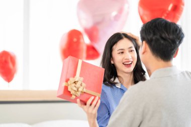 Asian couple Showing love surprise giving flowers or gifts to each other on important occasions such Valentine's Day birthdays or wedding anniversaries with love and warmth in bedroom of their home