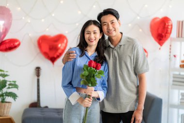 Asian couple Showing love surprise giving flowers or gifts to each other on important occasions such Valentine's Day birthdays or wedding anniversaries with love and warmth in bedroom of their home