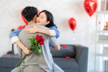 Asian couple Showing love surprise giving flowers or gifts to each other on important occasions such Valentine's Day birthdays or wedding anniversaries with love and warmth in bedroom of their home