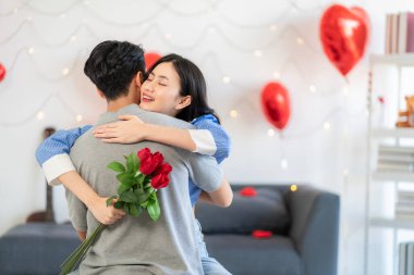 Asian couple Showing love surprise giving flowers or gifts to each other on important occasions such Valentine's Day birthdays or wedding anniversaries with love and warmth in bedroom of their home