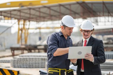 Erkek mühendisler, çalışanların çalışmalarını ve üretilmiş ürünlerin kalitesini standartlara uygun şekilde inceleyip kontrol ediyorlar. Prefabrik duvarlar üreten endüstriyel fabrikalarda