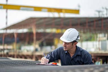 Erkek mühendisler, çalışanların çalışmalarını ve üretilmiş ürünlerin kalitesini standartlara uygun şekilde inceleyip kontrol ediyorlar. Prefabrik duvarlar üreten endüstriyel fabrikalarda
