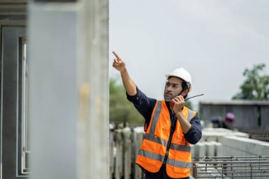 Erkek mühendisler, çalışanların çalışmalarını ve üretilmiş ürünlerin kalitesini standartlara uygun şekilde inceleyip kontrol ediyorlar. Prefabrik duvarlar üreten endüstriyel fabrikalarda