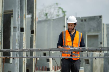 Erkek mühendisler, çalışanların çalışmalarını ve üretilmiş ürünlerin kalitesini standartlara uygun şekilde inceleyip kontrol ediyorlar. Prefabrik duvarlar üreten endüstriyel fabrikalarda