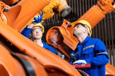 Bir grup mühendis bilgisayar kontrollü çelik kaynaklama robotlarını incelemek için toplanıyor. Provalar ve kullanım için kurulum planı.