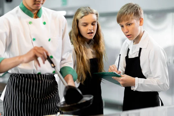 学生们正在一个配备标准厨房和全套设备的烹饪学院学习烹饪 并有一个专业的厨师作为教练 — 图库照片