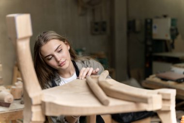 Dişi bir marangoz tasarladığı ve yaptığı sandalyeyi birleştiriyor. Evinde bulunan mobilya fabrikasında.