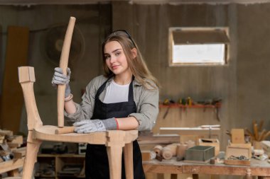 Dişi bir marangoz tasarladığı ve yaptığı sandalyeyi birleştiriyor. Evinde bulunan mobilya fabrikasında.