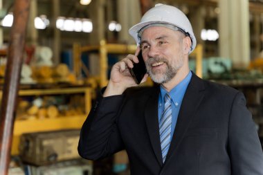 Bir işadamı, tren provaları için eski bir fabrikanın bakım işlerini kontrol ediyor. Müşterilerle ya da çalışanlarla telefonda konuşmak.