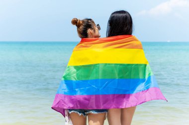 Plajda LGBTQ bayraklı lezbiyen çift, denizde birlikte tatilde mutlu çift.