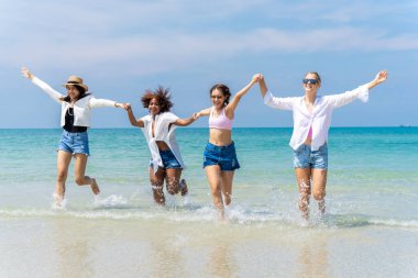 Farklı etnik kökenlere sahip bir grup kızın plajda birlikte koşup eğlendiği bir fotoğraf. Yeni bir günde