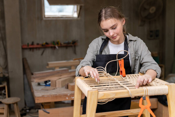 A female carpenter assembling a chair she had designed and built. At the furniture factory found inside her house