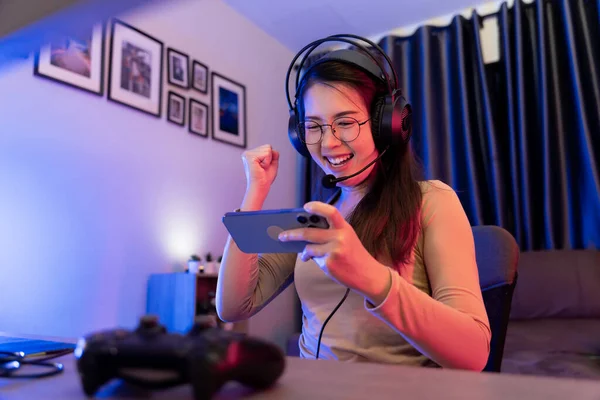 Asyalı modern bayan oyuncu RGB 'nin aydınlattığı bir oyun odasında ciddi bir oyun oynuyor..