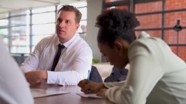 Genç bir erkek yöneticinin bir iş arkadaşıyla birlikte çalıştığı görüntüler. 