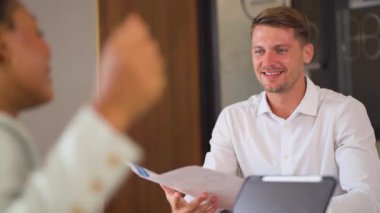 Genç bir erkek yöneticinin bir iş arkadaşıyla birlikte çalıştığı görüntüler. 