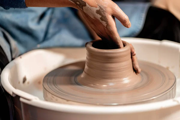 earthenware The art of sculpting clay with ceramics being molded by hand on a spinning machine. with the right posture to create a plate or vase professionally