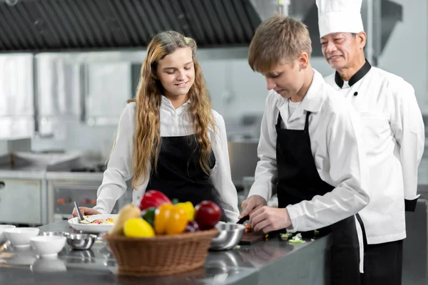 学生们正在一个配备标准厨房和全套设备的烹饪学院学习烹饪 并有一个专业的厨师作为教练 — 图库照片