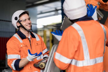 Bir grup erkek mühendis bilgisayar kontrollü çelik kaynaklama robotlarını incelemek için buluşuyor. Provalar ve kullanım için kurulum planı.