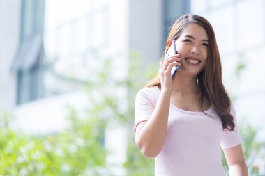 Asyalı kız öğrenci üniversite alanında sınavlara hazırlanıyor. İnternete bağlı cep telefonu ya da dizüstü bilgisayarla iletişim kurun. bir çok bilgi kaynağıyla