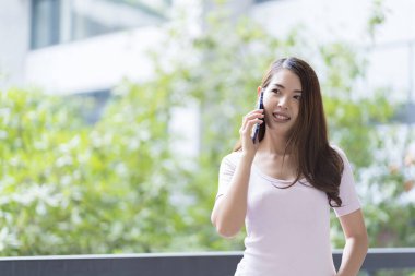 Asyalı kız öğrenci üniversite alanında sınavlara hazırlanıyor. İnternete bağlı cep telefonu ya da dizüstü bilgisayarla iletişim kurun. bir çok bilgi kaynağıyla