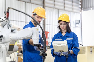 Erkek ve kadın mühendislerden oluşan bir ekip bilgisayar kontrollü çelik kaynaklama robotlarını incelemek için toplanıyor. Provalar ve kullanım için kurulum planı.