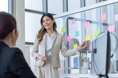 Bir grup Asyalı genç iş adamı mutlu mesut konuşup eğleniyor. Şirketin ofisinde.