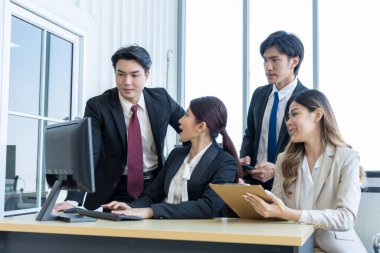 Bir grup Asyalı genç iş adamı mutlu mesut konuşup eğleniyor. Şirketin ofisinde.