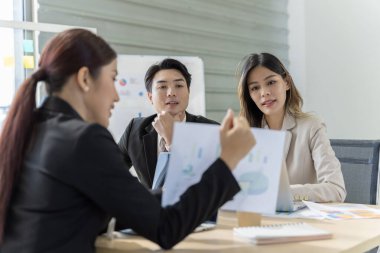 Bir grup Asyalı genç iş adamı mutlu mesut konuşup eğleniyor. Şirketin ofisinde.