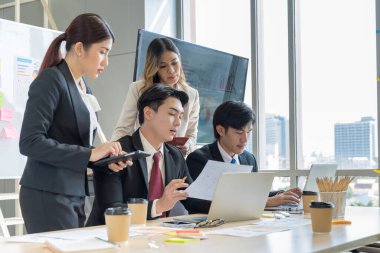 Bir grup Asyalı genç iş adamı mutlu mesut konuşup eğleniyor. Şirketin ofisinde.