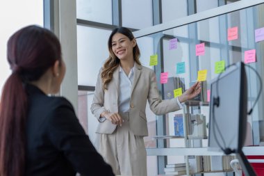 Bir grup Asyalı genç iş adamı mutlu mesut konuşup eğleniyor. Şirketin ofisinde.