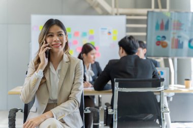 Bir grup Asyalı genç iş adamı mutlu mesut konuşup eğleniyor. Şirketin ofisinde.