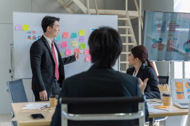 Bir grup Asyalı genç iş adamı mutlu mesut konuşup eğleniyor. Şirketin ofisinde.