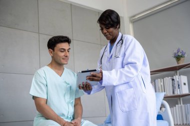 Kadın doktor ve erkek hasta konuşuyor ve hastanedeki hastaların hastalıkları hakkında tavsiyelerde bulunuyor.