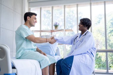 Kadın doktor ve erkek hasta konuşuyor ve hastanedeki hastaların hastalıkları hakkında tavsiyelerde bulunuyor.