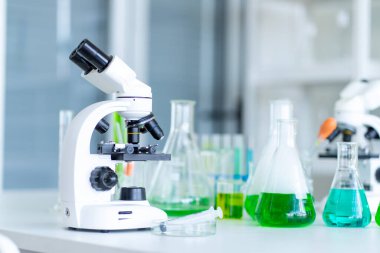 Bir mikroskop ve bir sürü test tüpü içeriyor. Okuldaki laboratuvarda. 