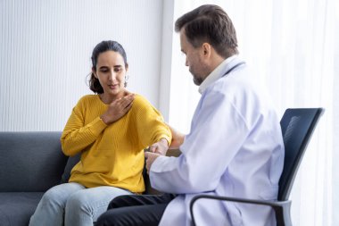 Erkek doktor ve kadın hasta konuşuyor ve hastanedeki hastaların hastalıkları hakkında tavsiyelerde bulunuyor.