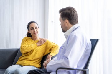 Erkek doktor ve kadın hasta konuşuyor ve hastanedeki hastaların hastalıkları hakkında tavsiyelerde bulunuyor.